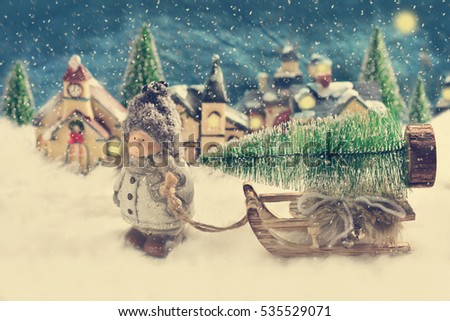 winter night scene with a boy pulling a sled with christmas tree