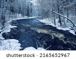 Winter nonfreezing stepped bed river in the snow-covered banks. Northern Europe