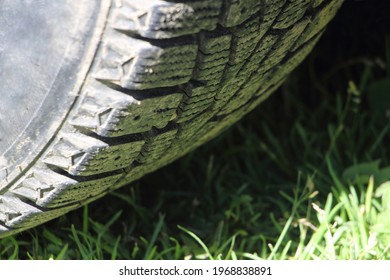 Winter non-studded tire on green grass countryside road in summer, year-round tire useWinter non-studded tire on green grass in summer, all season M+S tyres use