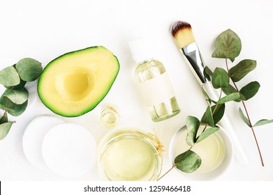 Winter Nourishing Skincare. Fresh Avocado Face Mask And Bowls Of Healing Oil, Green Aromatic Eucalyptus Plant Leaves. Natural Beauty Treatment Ingredients, Flat Lay.