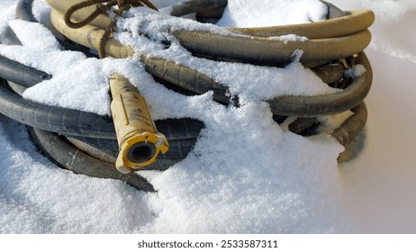 Winter, on the snow lies a thick hose, coiled into rings from a sandblasting machine, a Baynet type connection. - Powered by Shutterstock