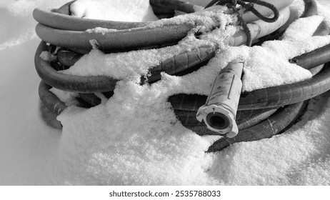 Winter, on the snow lies a thick hose, coiled into rings from a sandblasting machine, a Baynet type connection. - Powered by Shutterstock