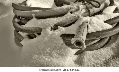 Winter, on the snow lies a thick hose, coiled into rings from a sandblasting machine, a Baynet type connection. - Powered by Shutterstock