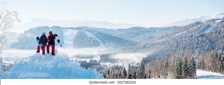 Winter Panorama Of The Carpathians Mountains Landscape And Forests In A White Haze And In The Side Stand On A Snowdrift Snow Two Snowboarders Back To The Camera