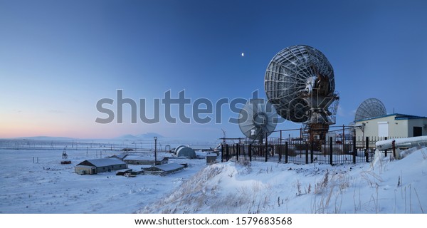 Winter panorama with large satellite dishes.\
Telecommunications in the Arctic. Industrial landscape with\
antennas. Morning twilight. Location place: Anadyr, Chukotka,\
Siberia, Far East of Russia.\
