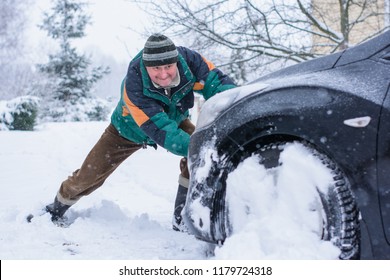 Winter, people and car problem concept. Man are pushing the car, stuck in the snow. Mutual aid. Winter problem. transportation, winter and vehicle concept - closeup of man pushing car stuck in snow