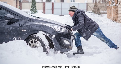 Winter, People And Car Problem Concept. Man Try On Pushing The Car, Stuck In The Snow. Mutual Aid. Winter Problem. Transportation, Winter And Vehicle Concept - Closeup Of Man Pushing Car Stuck In Snow