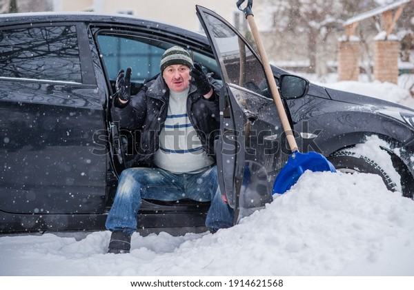 Winter, people and car problem concept. Man try on\
pushing the car, stuck in the snow. Mutual aid. Winter problem.\
transportation, winter and vehicle concept - closeup of man pushing\
car stuck in snow