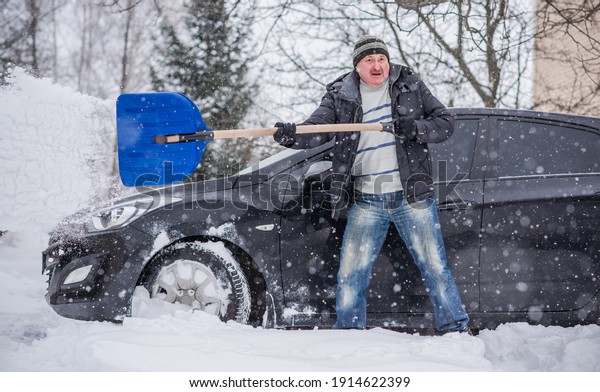 Winter, people and car problem concept. Man try on\
pushing the car, stuck in the snow. Mutual aid. Winter problem.\
transportation, winter and vehicle concept - closeup of man pushing\
car stuck in snow