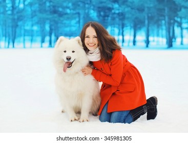 Winter And People Concept - Happy Smiling Woman Having Fun With White Samoyed Dog Outdoors On Snow