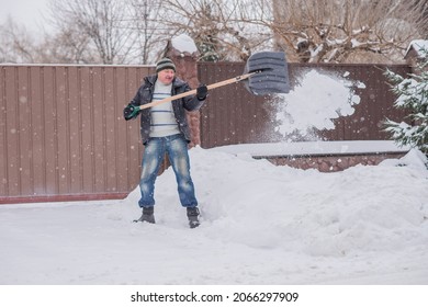 Winter, People And Snow Problem Concept - Man Digging Snow With Shovel At Yard. Man Standing With Blue Shovel, Cleaning. 