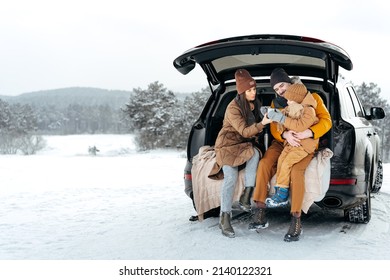 Winter portrait of a family sit on car trunk enjoy their vacation in forest - Powered by Shutterstock