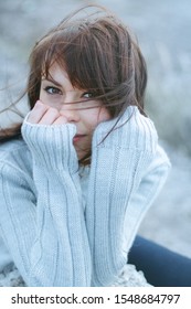 Winter portrait of a girl in sweater. Close up woman freezing outdoor portrait . Blue colors, hair and wind.