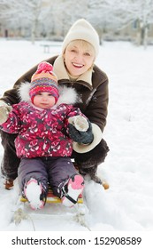 Winter Portrait Of Grandmother And Granddaughter On Sleight