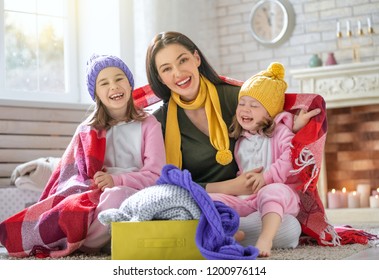 Winter portrait of happy loving family wearing knitted sweaters. Mother and children girls having fun, playing and laughing at home. Fashion concept.