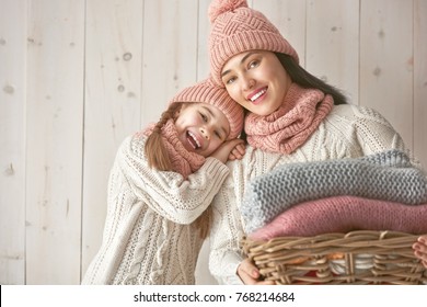 Winter Portrait Of Happy Loving Family Wearing Knitted Hats, Snoods And Sweaters. Mother And Child Girl Having Fun, Playing And Laughing On White Wooden Background. Fashion Concept.