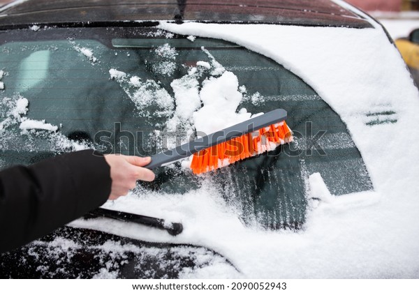 Winter problems with the car. A man cleans the car\
from snow with a brush