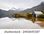 Winter reflections of a mist shrouded Cradle Mountain and boatshed in the calm waters of Dove Lake at the northern end of Tasmania