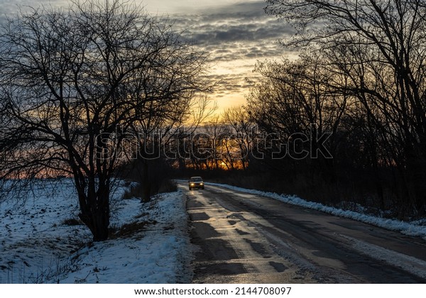 Winter road against the backdrop\
of a sunny sunset. Direction of movement. Car route. Sunny sunset.\
Morning sunrise. White snow. Evening twilight. Road\
markings.