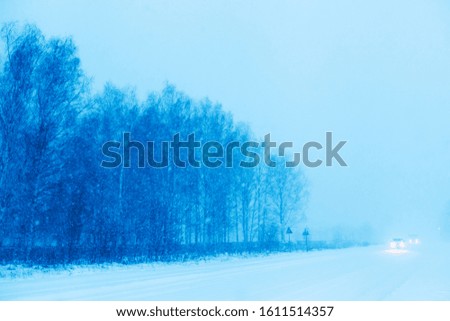 Winter road in the forest. A beautiful, winter landscape with cars in the background.