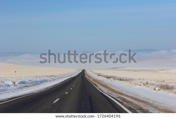 Winter road\
leaving into distance into the\
mountains