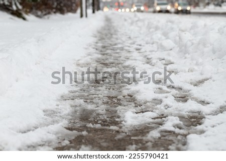 Winter road with melting from salt snow. Close up of sidewalk with slush on snowy day.