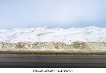 Winter road outside the city, cleared of snow in the countryside. Large snowdrifts on the side of the road.