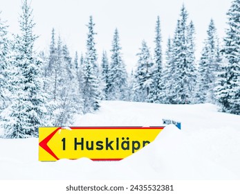 Winter Road Sign Indicating Huskläppen Amidst Snow-covered Trees in Sweden - Powered by Shutterstock