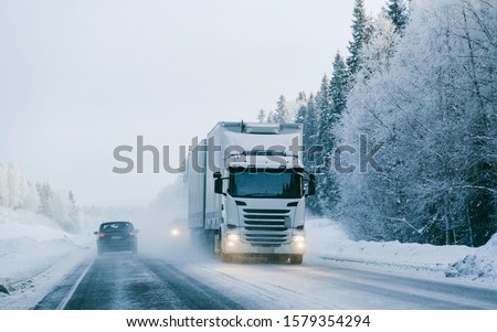 Winter road with snow. Truck in Finland. Lorry car and cold landscape of Lapland. Europe forest. Finnish City highway ride. Roadway and route snowy street trip. Delivery in downhill driveway driving