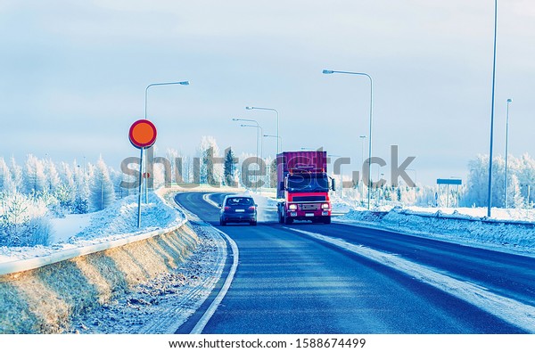 Winter road\
with snow. Truck in Finland. Lorry car and cold landscape of\
Lapland. Europe forest. Finnish City highway ride. Roadway and\
route snowy street trip.  Selective\
focus