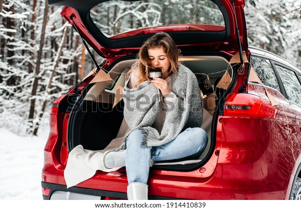 winter\
romance concept car travel in winter, in red car drinks hot tea\
from a thermos, picnic in a frosty winter\
forest