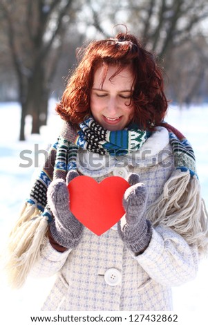 Winter romantic girl holding a red heart