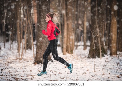 Winter Running Exercise. Runner Jogging In Snow. Young Woman Fitness Model Running In A City Park 