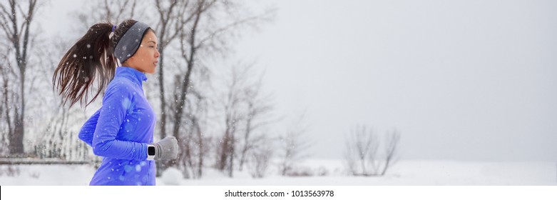 Winter Running Smartwatch Woman In Cold Snow Weather Jogging Outside Wearing Windproof Clothes With Gloves, Headband, Winter Tights And Wind Jacket In White Snowfall Background.