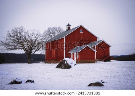 Winter rural road travel landscape in New England of America with bare trees, snow-covered hills, and barns
