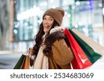 Winter sales and consumerism. Happy European woman holding shopping bags and smiling, carrying purchases after successful shopping