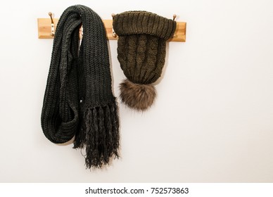 Winter scarf and wool cap with a furry ball and hanging on a hat stand on white background - Powered by Shutterstock