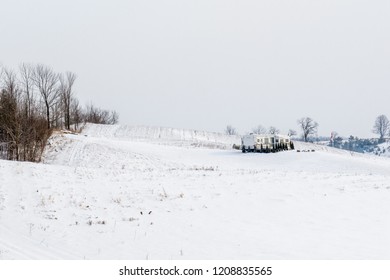 Winter Scene Featuring Camper Trailer In The Middle Of Valley Showing Ground Covered In Light White Snow And Brown Forest Trees