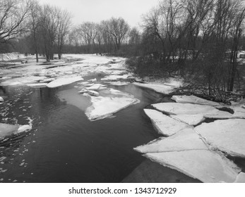 Winter Scene Featuring Icy River With Chunks Of Ice Breaking Off The Shore 