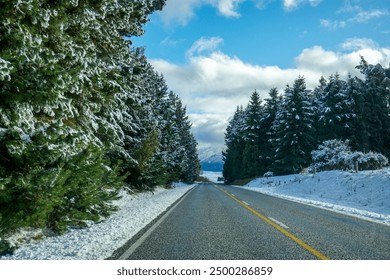 A winter scene on Crown Range Road, Queenstown, New Zealand. Snow-covered hills and a winding road lined with snowy trees, distant mountains, and a clear blue sky, road with snow, mountains remarkable - Powered by Shutterstock