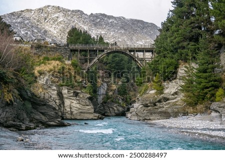 A winter scene on Crown Range Road, Queenstown, New Zealand. Edith Cavell Bridge spans the crystal-clear Shotover River with rocky canyons, snow-covered mountains, and forests,  wanaka, arthus point