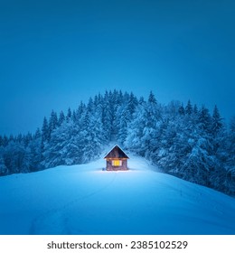 A winter scene with a solitary wooden cabin and snow-covered fir trees in the midst of a forested mountain meadow. Christmas postcard. Snowy mountains forest - Powered by Shutterstock