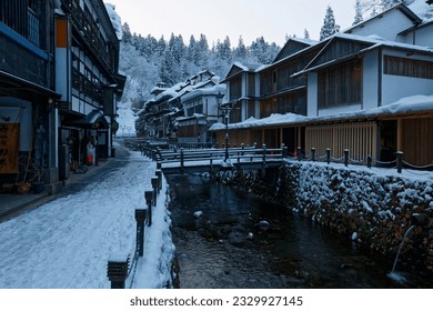 Winter scenery of Ginzan Onsen, a famous hot-spring resort town in Obanazawa, Yamagata, Japan, with antique wooden buildings of traditional Japanese Ryokan on the riverside covered by heavy snow - Powered by Shutterstock