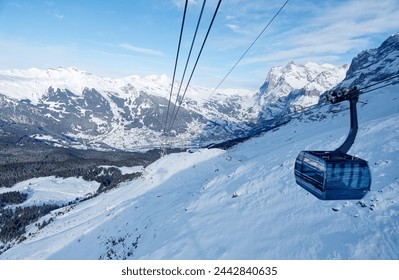 Winter scenery of Grindelwald village in the snowy valley with Wetterhorn mountain under blue sky in background, viewed from a gondola of Eiger Express cableway, in Berner Oberland, Switzerland - Powered by Shutterstock