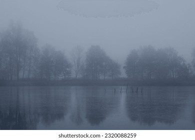 Winter scenery over the frozen misty lake with trees around it.