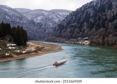 Winter scenery of a sightseeing boat cruising on Mogami-Gawa 最上川 (mogami-kyo Gorge), one of the three most rapid rivers in Japan, with the riverside mountains covered by snow in Yamataga Tohoku - Powered by Shutterstock