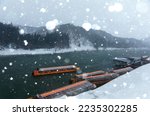 Winter scenery of tourist boats cruising on Mogami-Gawa, one of the three most rapid rivers in Japan, with the riverside hills covered by heavy snow on a cold snowy morning in Yamataga, Tohoku, Japan