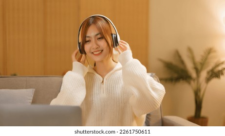 Winter season concept, Young woman wearing headphone to listening music on laptop in night time. - Shutterstock ID 2261750611
