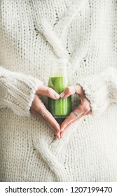 Winter Seasonal Smoothie Drink Detox. Female In Warm Sweater Holding Bottle Of Green Smoothie Or Juice Making Heart Shape With Her Hands. Clean Eating, Weight Loss, Healthy Dieting Food Concept