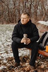 Winter Serenity: 40-Year-Old Man Enjoying Tea On Snow-Covered Bench In Rural Park. Immerse Yourself In The Tranquil Beauty Of Winter As A 40-year-old Man Finds Solace On A Snowy Bench In A Rural Park.